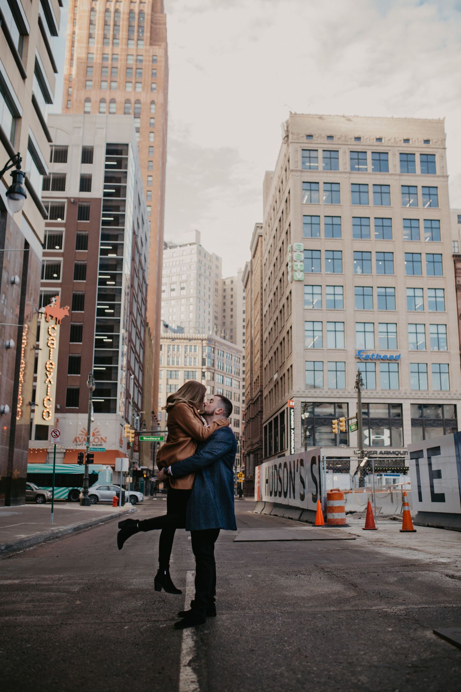 A romantic lift pose between tall city buildings on an urban street.