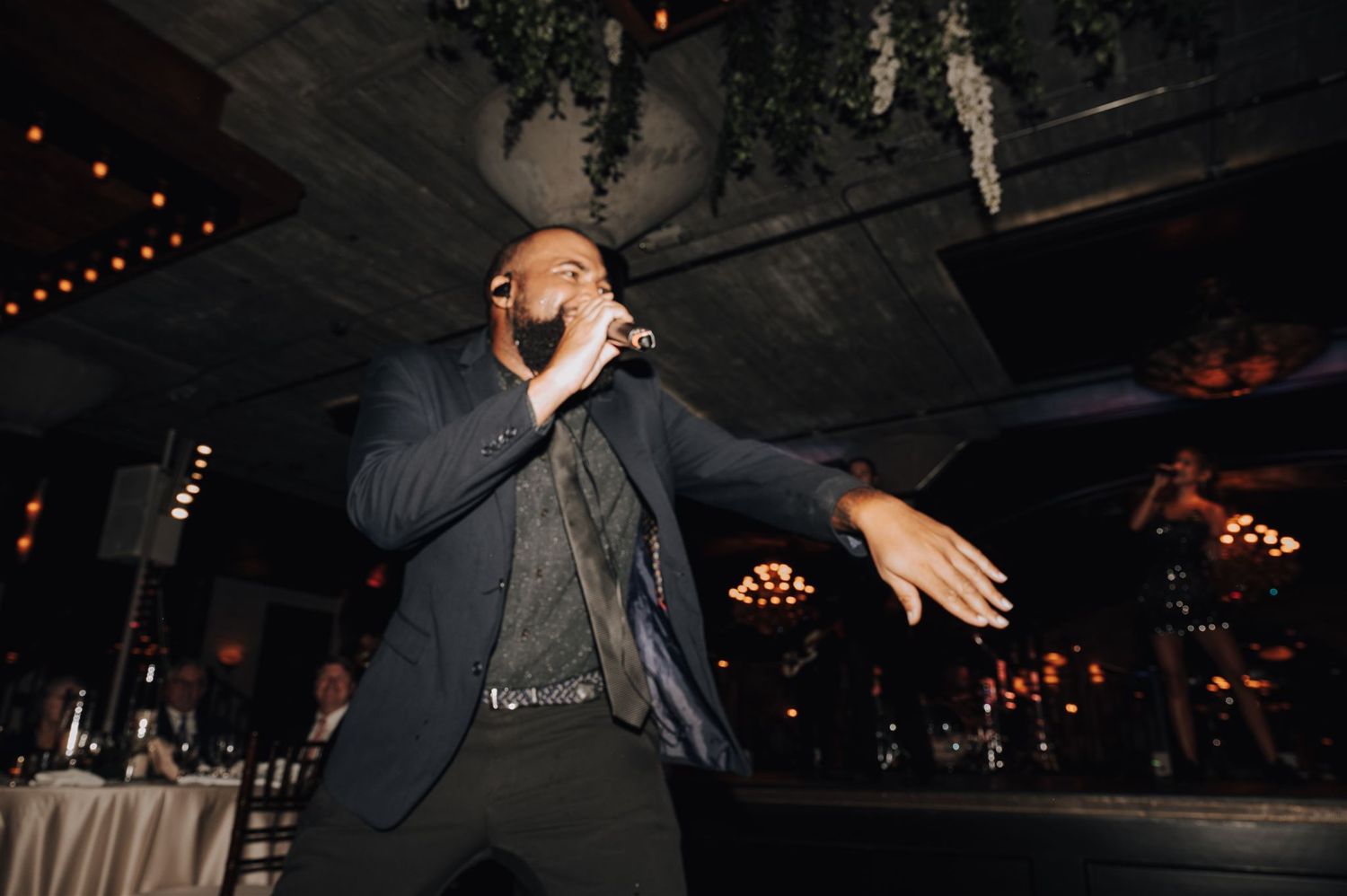Performer singing passionately on stage during evening entertainment at event venue.
