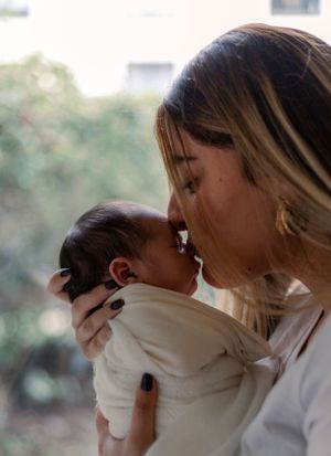 A tender moment between mother and newborn baby captured in soft natural light.