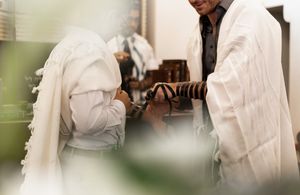Traditional Jewish wedding ceremony with participants in white prayer shawls.