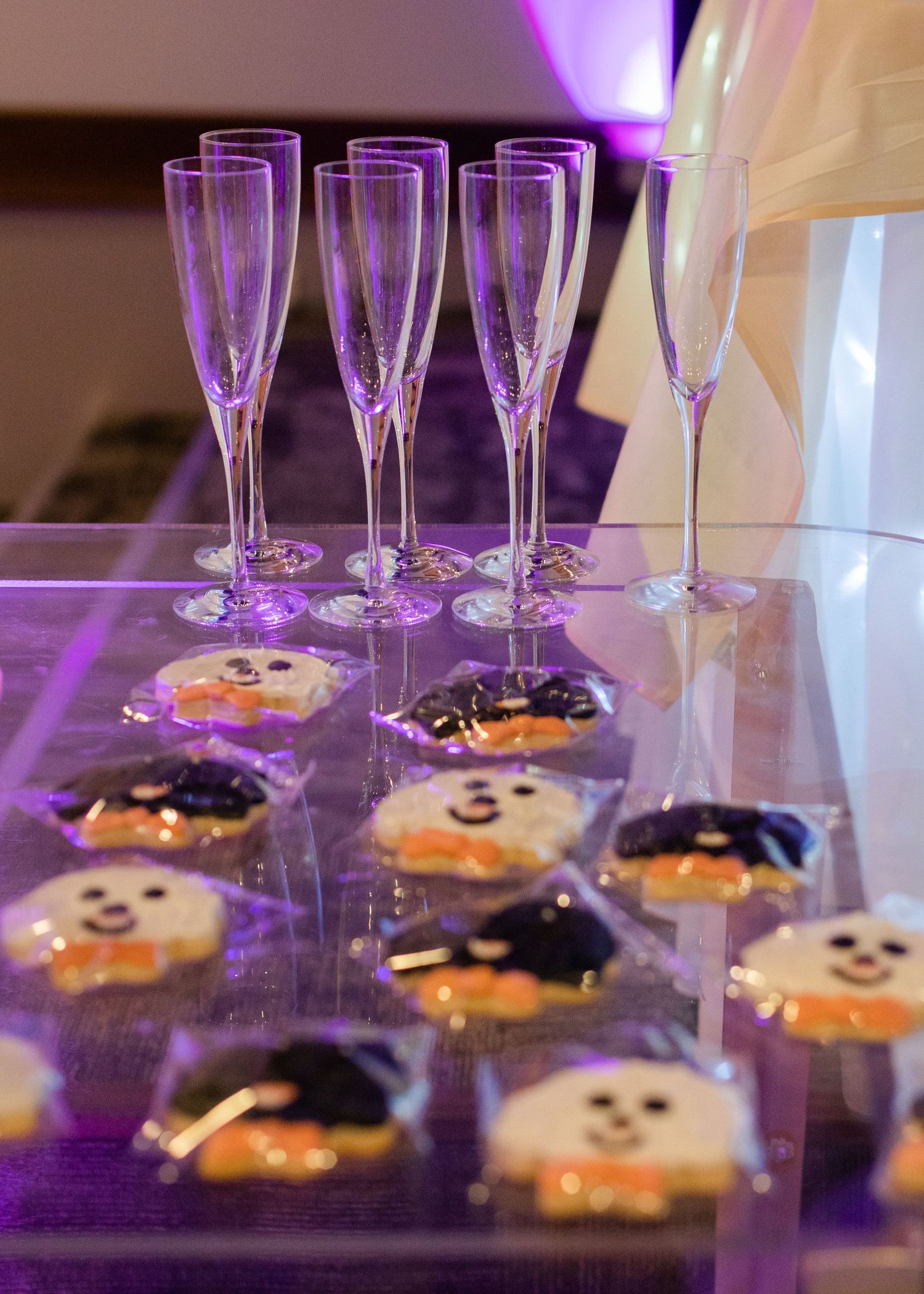 Halloween-themed wedding cookies displayed with champagne flutes under purple lighting.