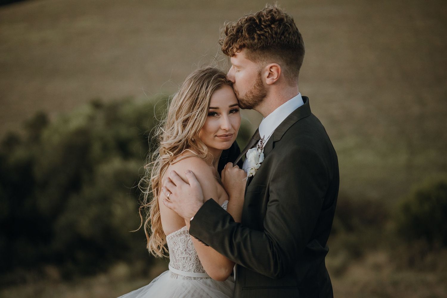 Close embrace of bride and groom during outdoor wedding photoshoot.