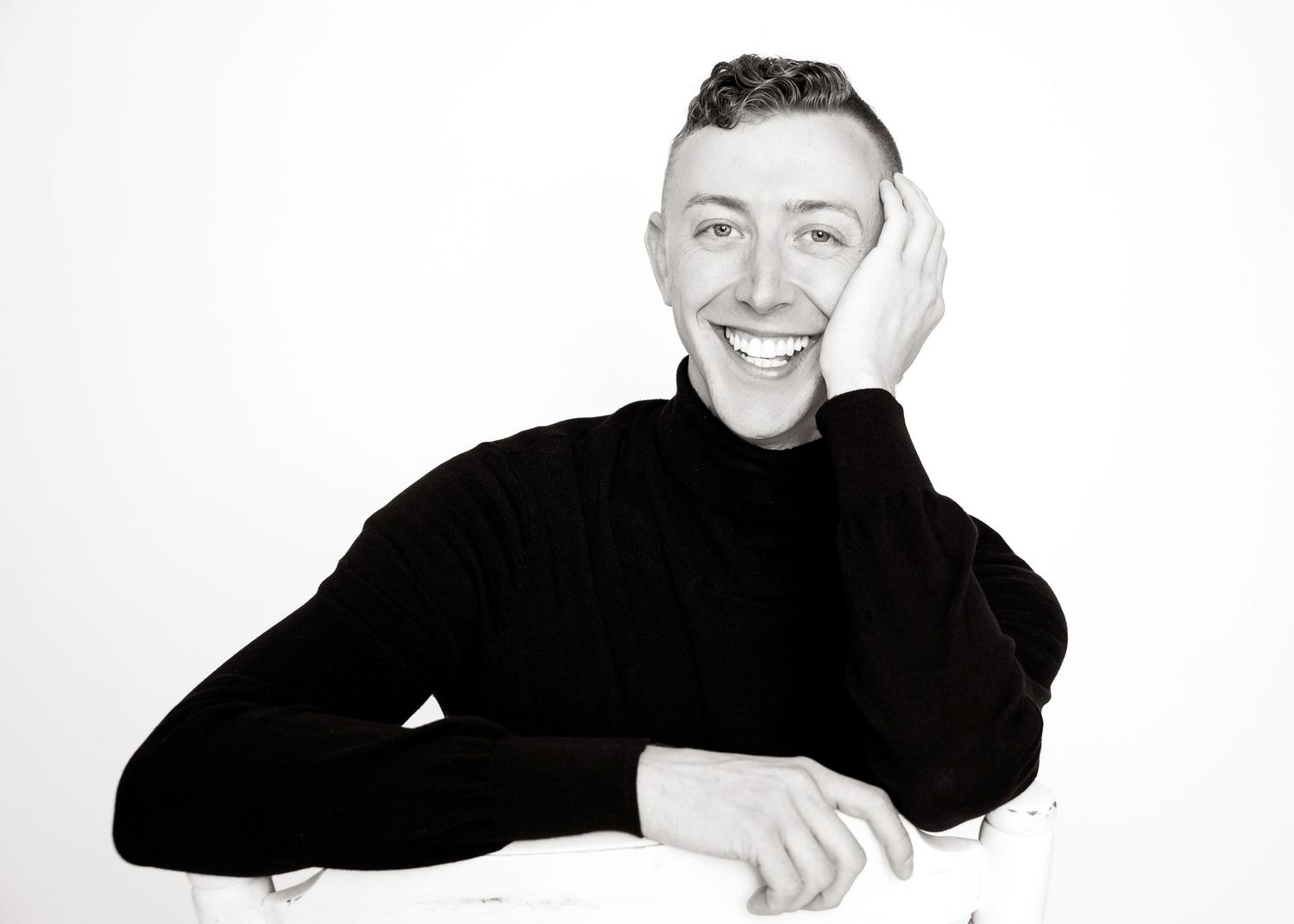 Black and white portrait of person in turtleneck sweater with hand on face.