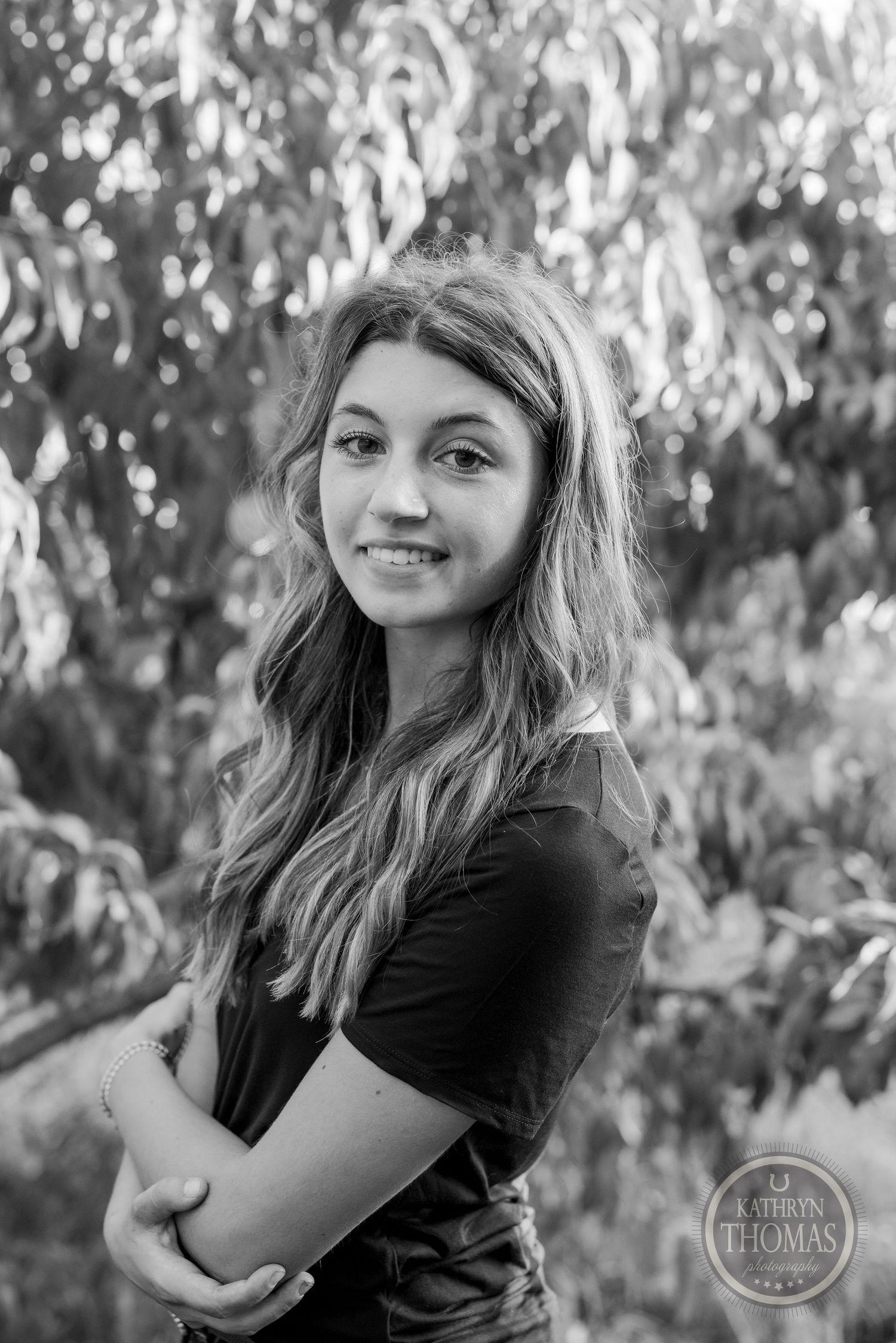 Black and white portrait with soft lighting and natural foliage background.