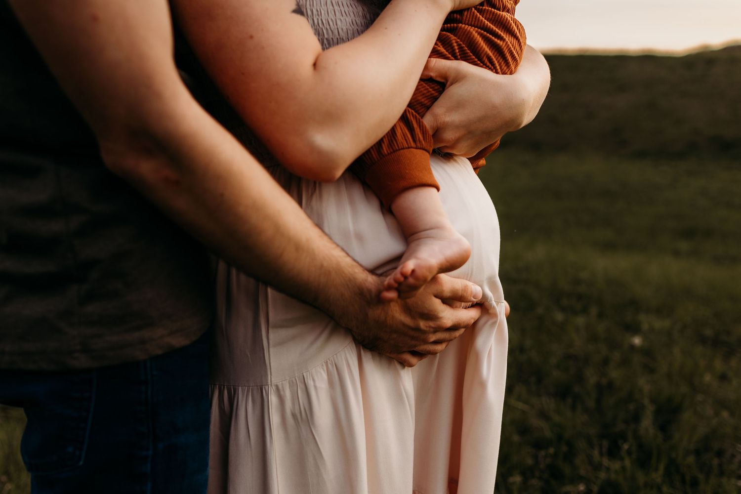 Intimate moment captured between figures in soft evening light against rural backdrop.