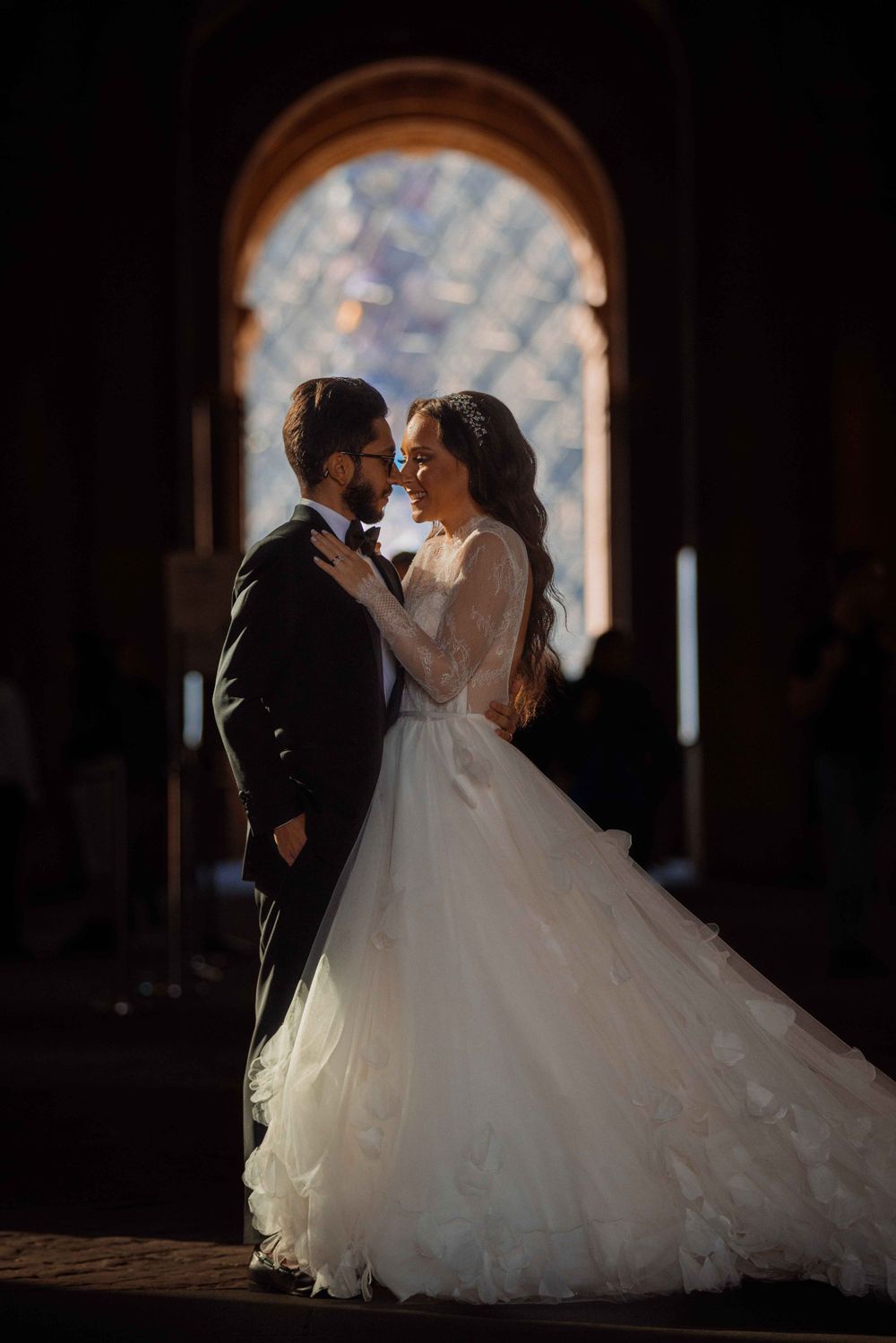 Wedding couple sharing an intimate moment under a dramatic stone archway.