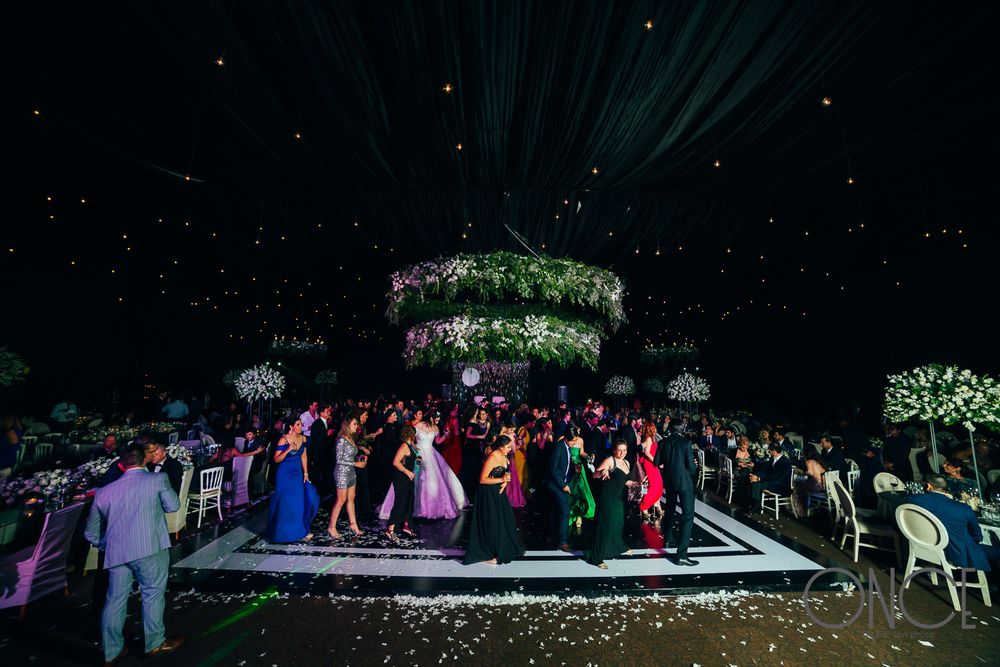 Nighttime wedding reception dance floor under a spectacular greenery chandelier with twinkling lights.