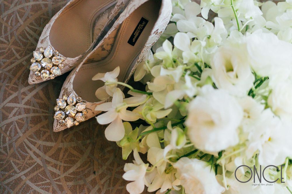 Elegant bridal shoes with crystal embellishments next to a white floral bouquet.