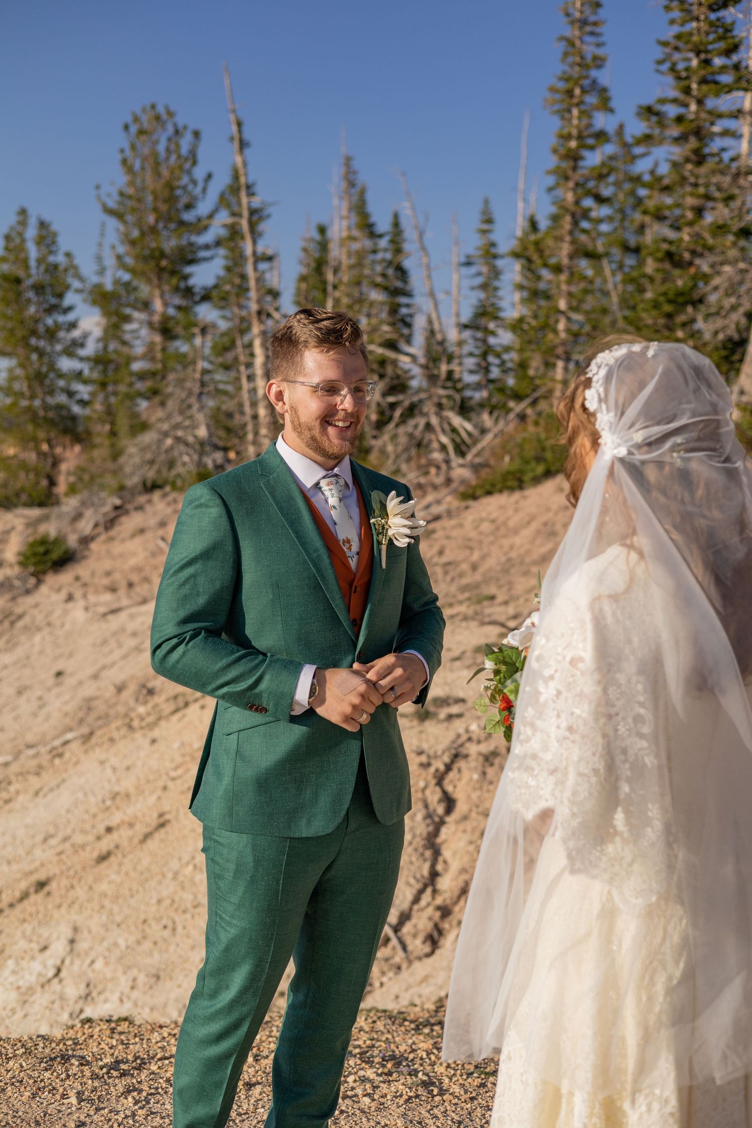 Wedding couple shares moment in mountain setting with pine trees.