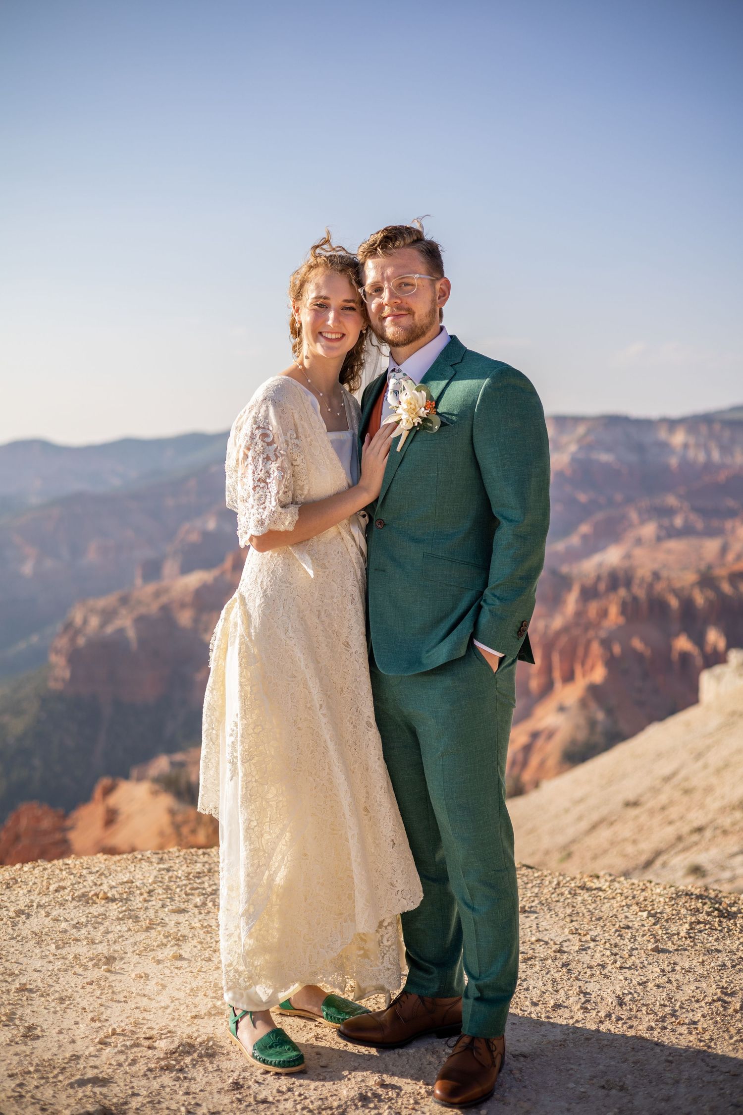 Wedding couple shares an intimate moment while standing on a rocky canyon cliff.