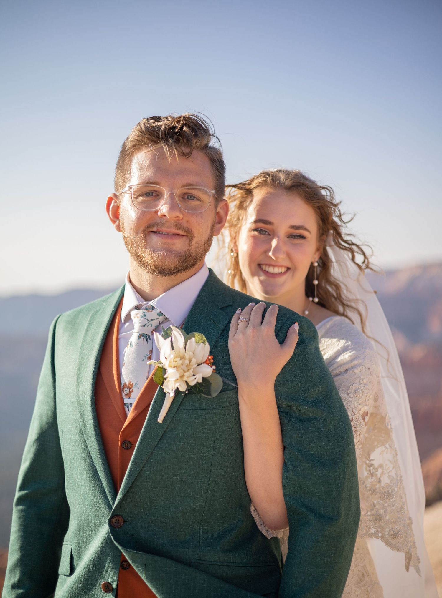 Happy couple in wedding attire smiles and laughs together with canyon views in the background.