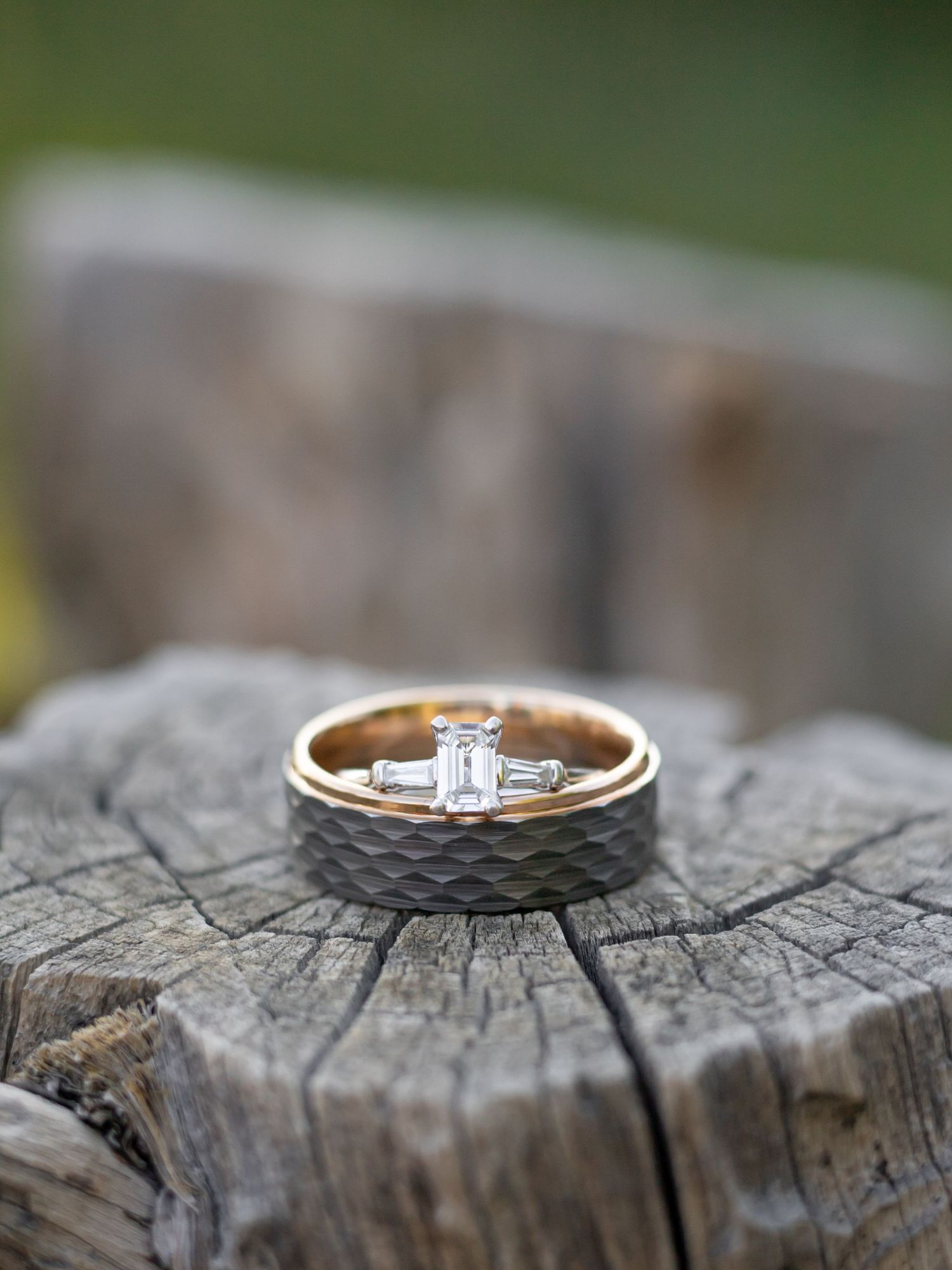 Wedding rings displayed on weathered wood with shallow depth of field.