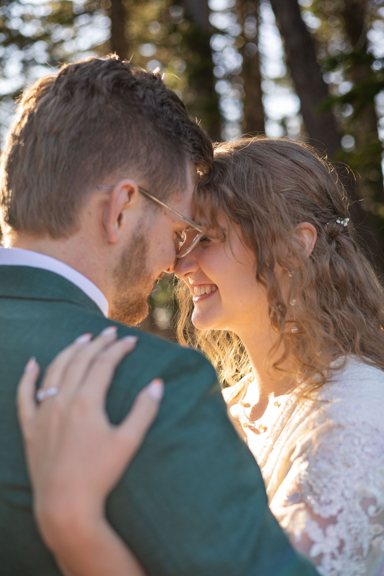 Sunlit couple shares an intimate moment in a forest setting during their wedding.