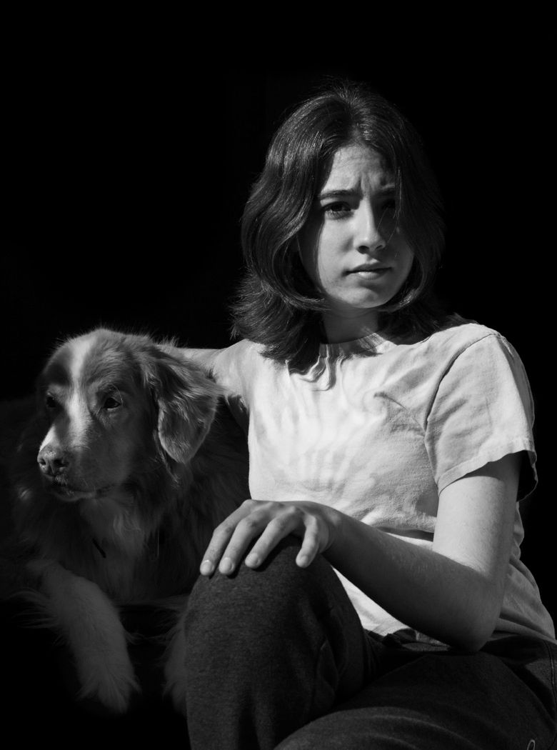 Monochrome portrait of a pensive young woman sitting with her contemplative dog companion.