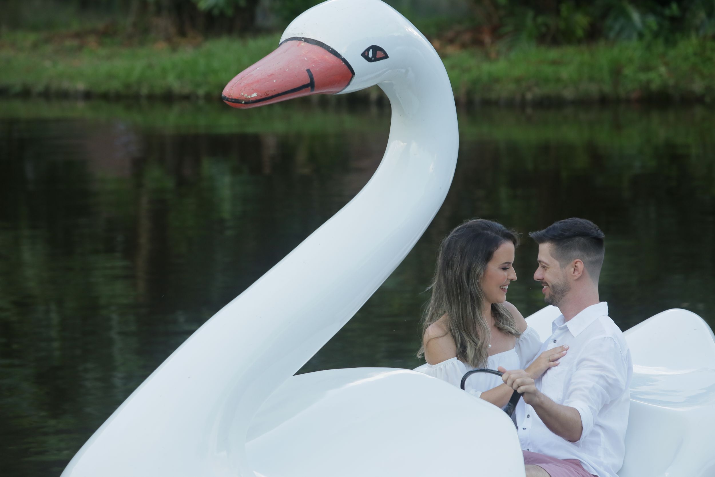White swan pedal boat creates romantic setting for couple on tranquil lake.