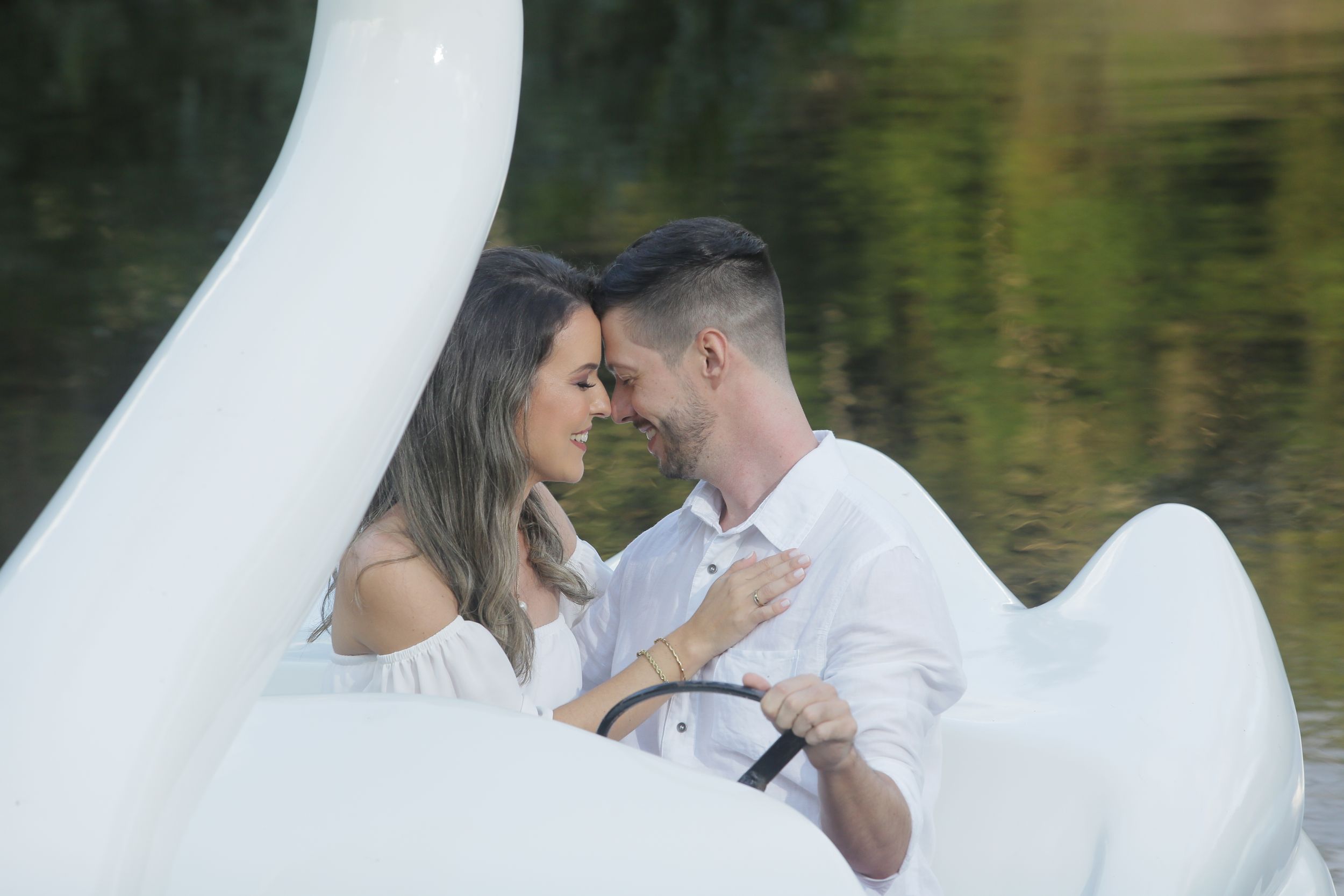Swan boat glides across reflective water during romantic photoshoot.