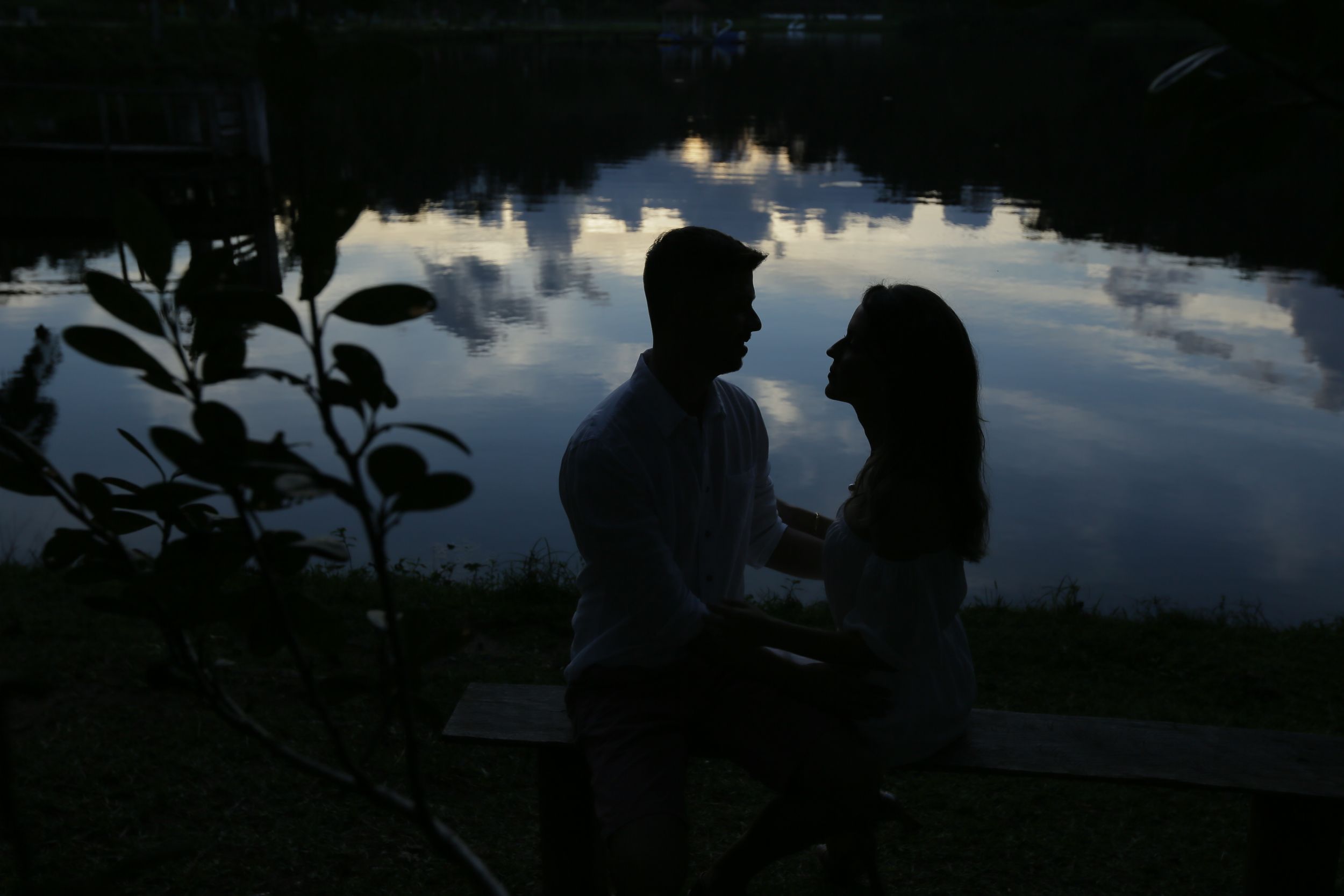 Silhouettes against sunset sky create dramatic romantic scene by water.