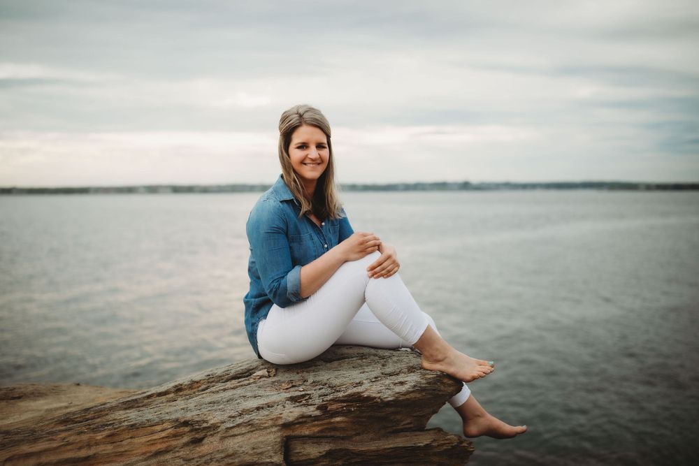 A casual portrait on rocky coastline at sunset wearing denim and white.