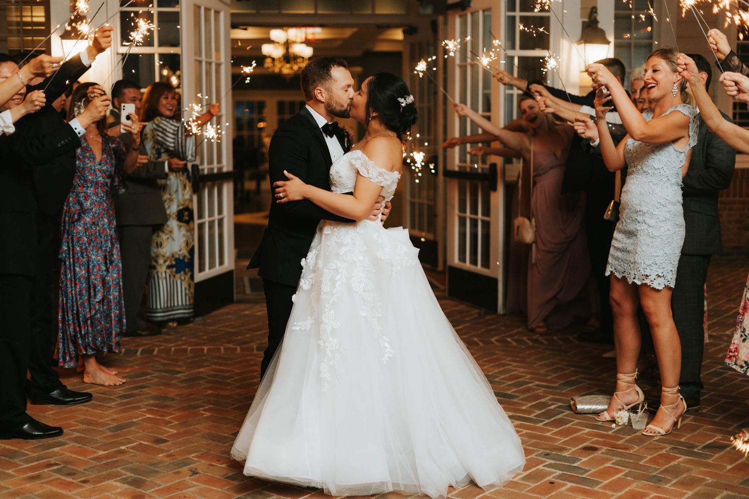 Newlyweds share their first dance surrounded by cheering guests at indoor reception.