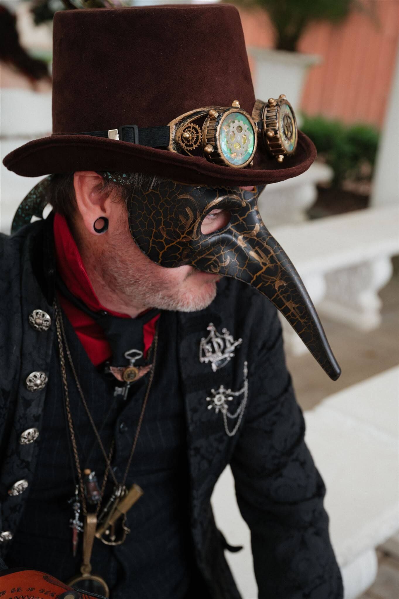 Ornate steampunk costume featuring a brown top hat, plague doctor mask, and vintage timepiece accessories.