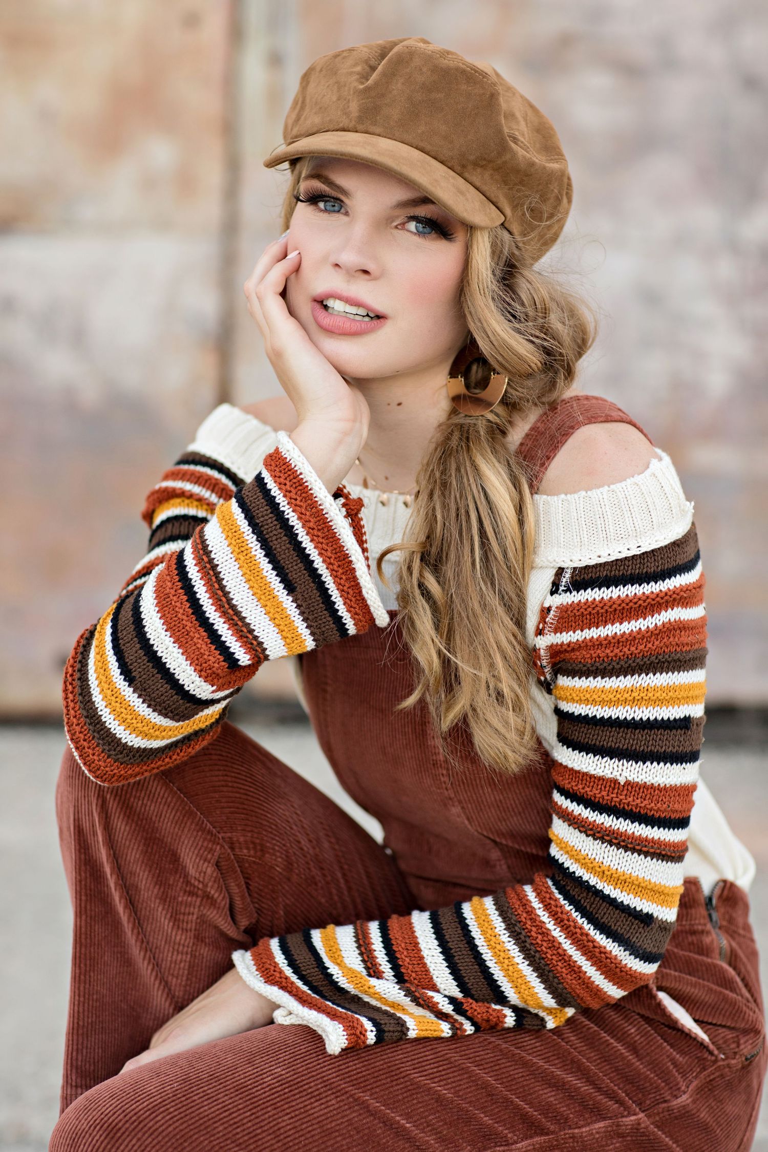 Autumn fashion portrait with brown newsboy cap, striped sleeves sweater and long blonde braid.