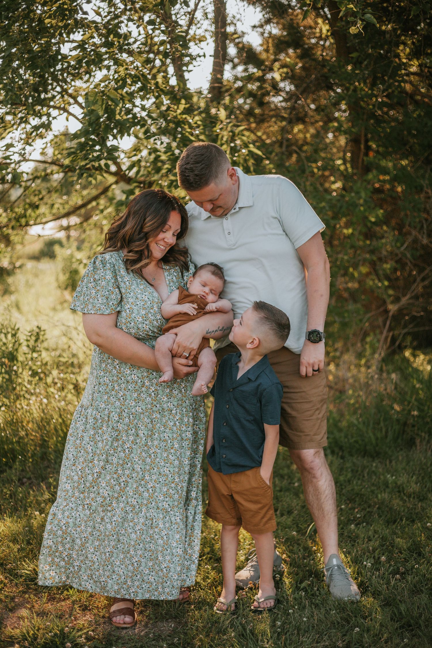 A family shares an intimate moment together in a sun-dappled outdoor setting.