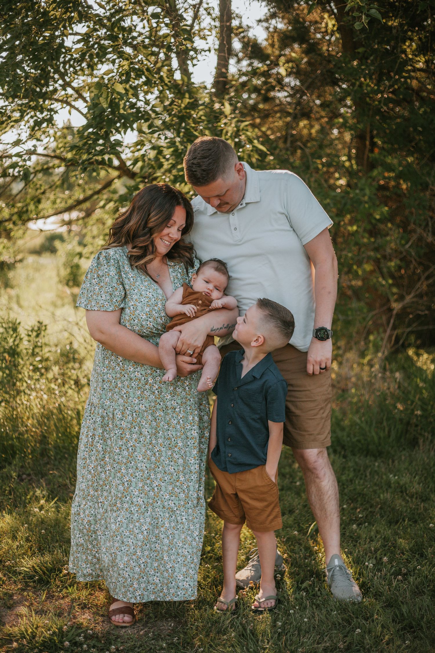 A family shares a loving moment together in a natural outdoor setting during golden hour.