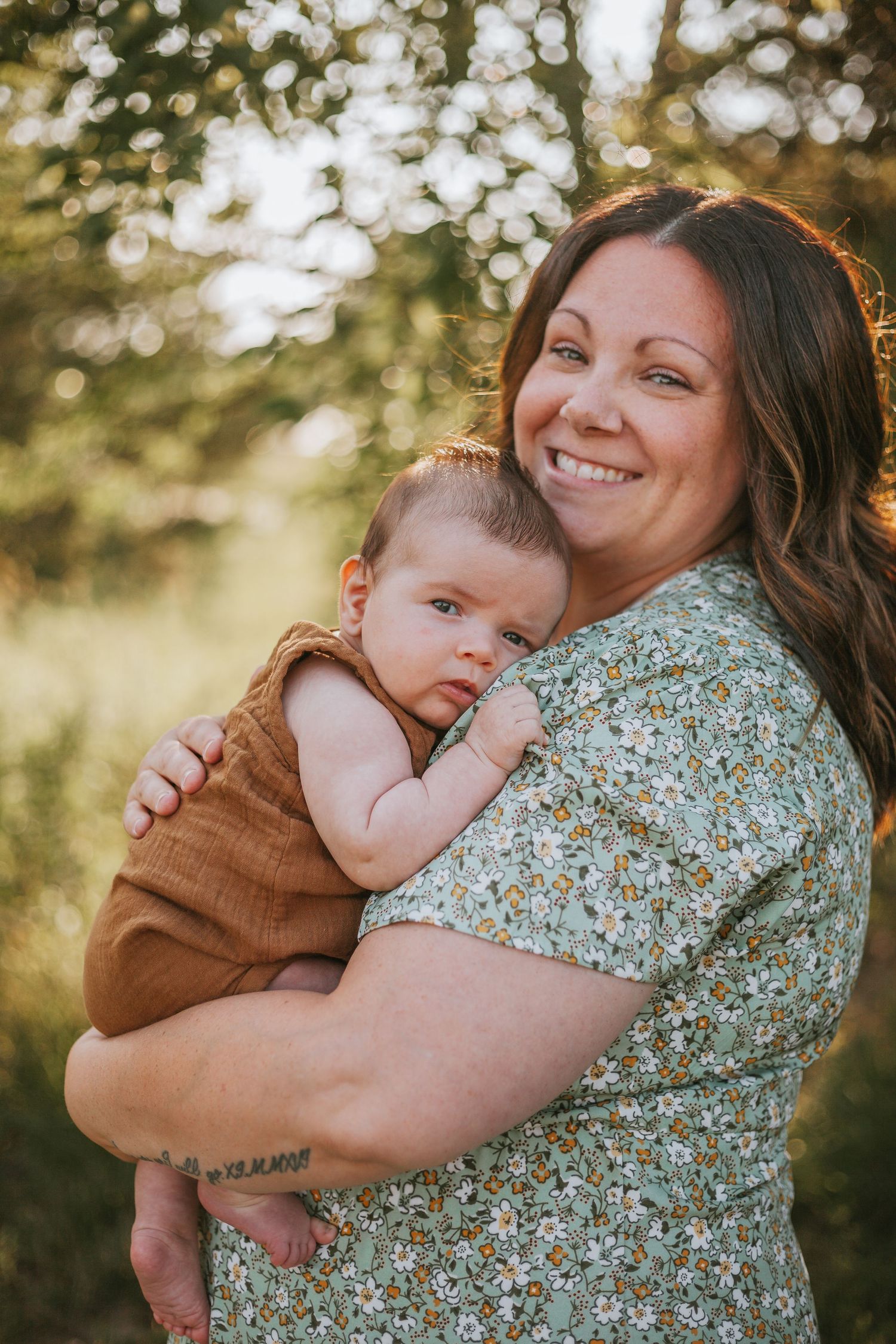 A tender embrace captured in golden sunlight against a natural bokeh background.