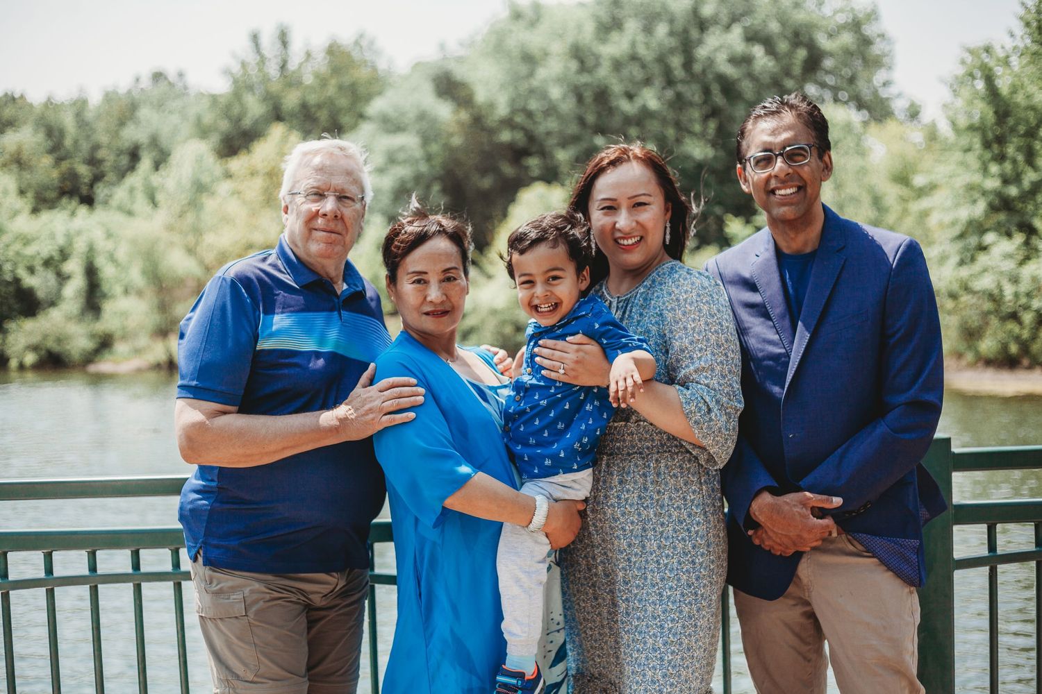 Candid family moments captured on a wooden bridge over water with natural greenery.