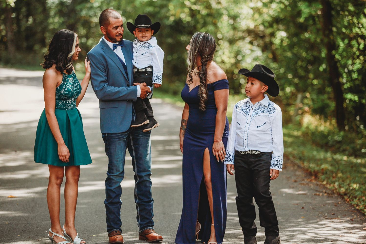Formal family gathering on a tree-lined path with coordinated outfits.
