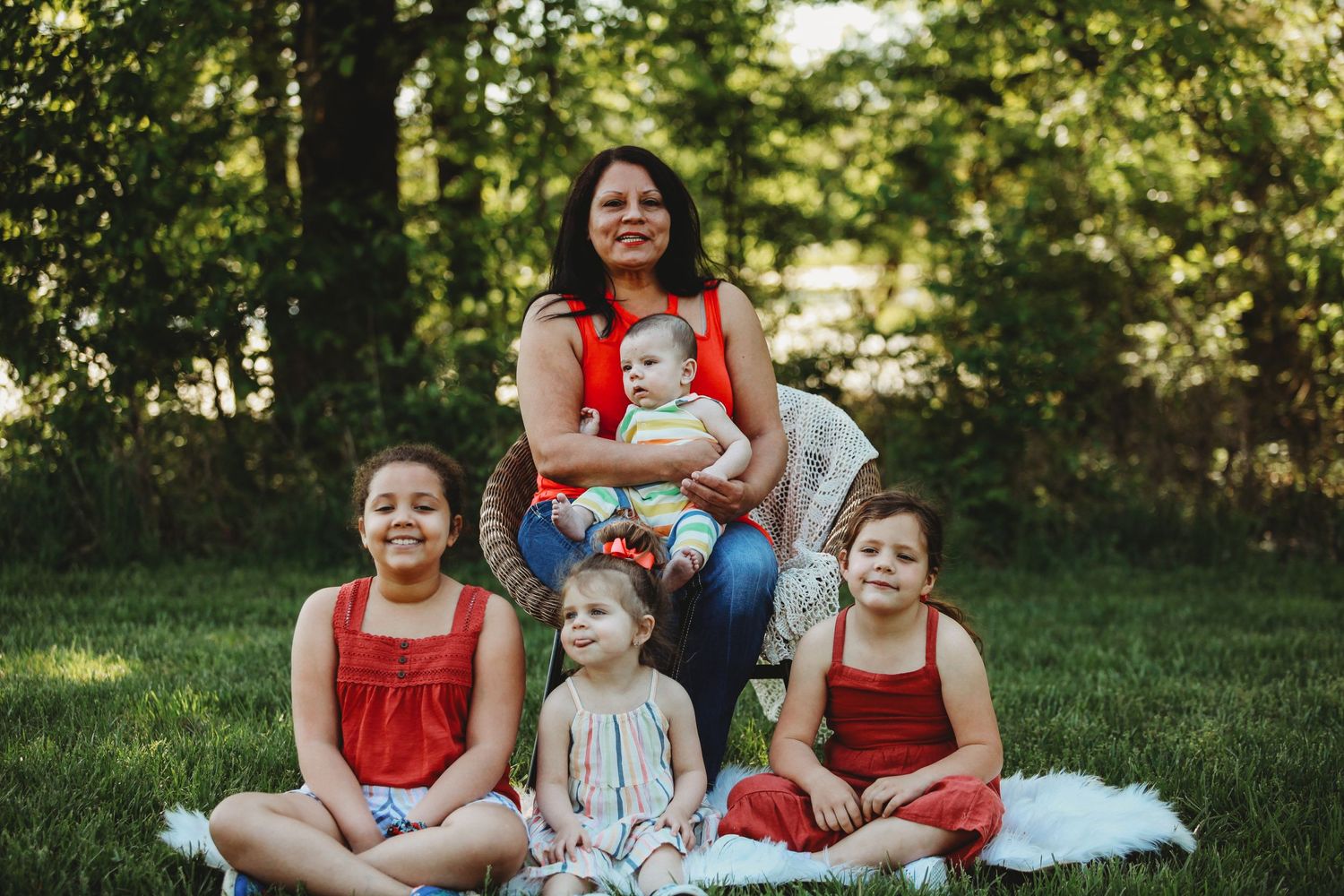 Group sitting together on grass wearing red and white coordinated outfits during outdoor photo session.