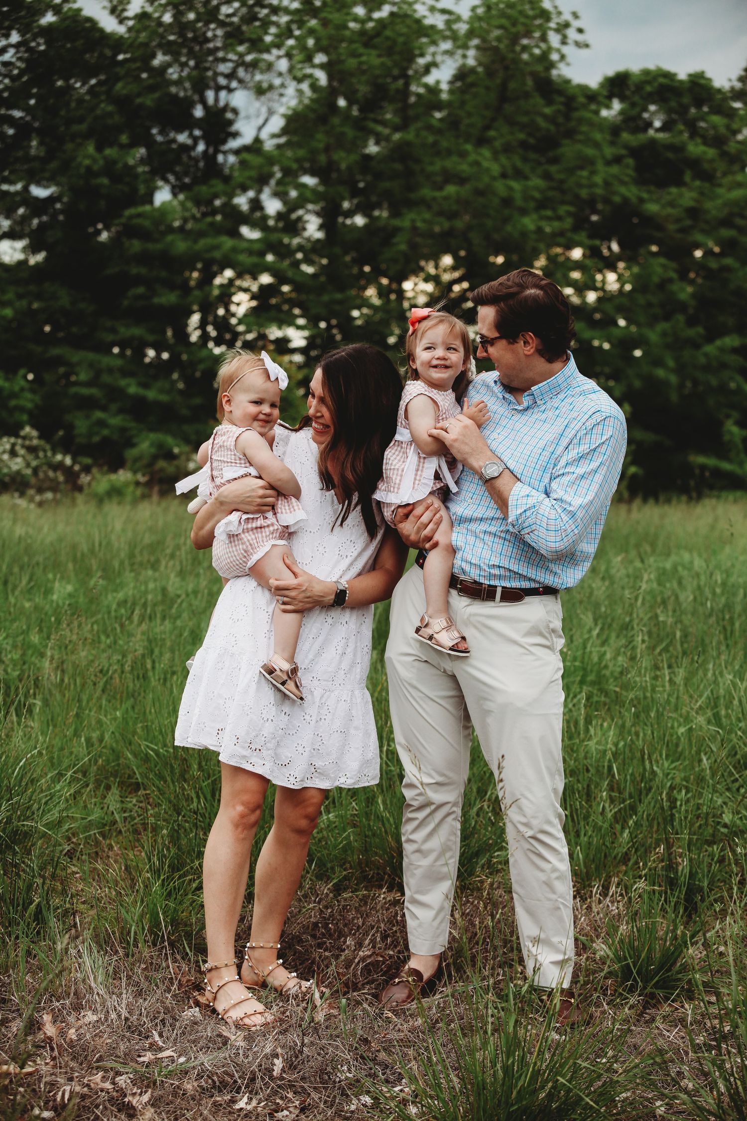 Family sharing intimate moments and laughter together in green summer field.