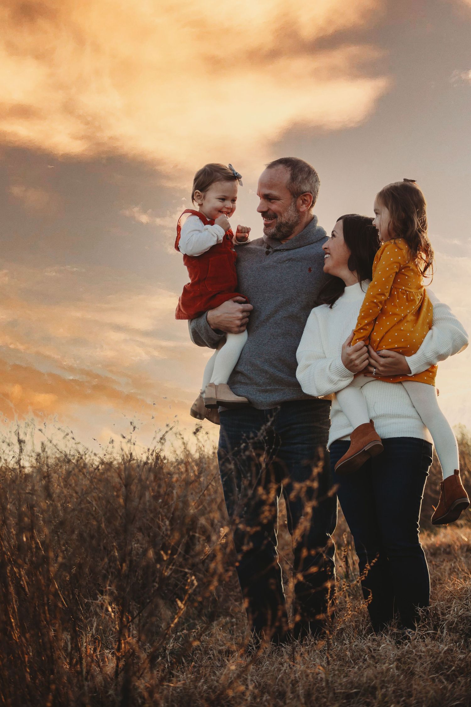 Family embracing in a field during sunset with warm autumn colors.