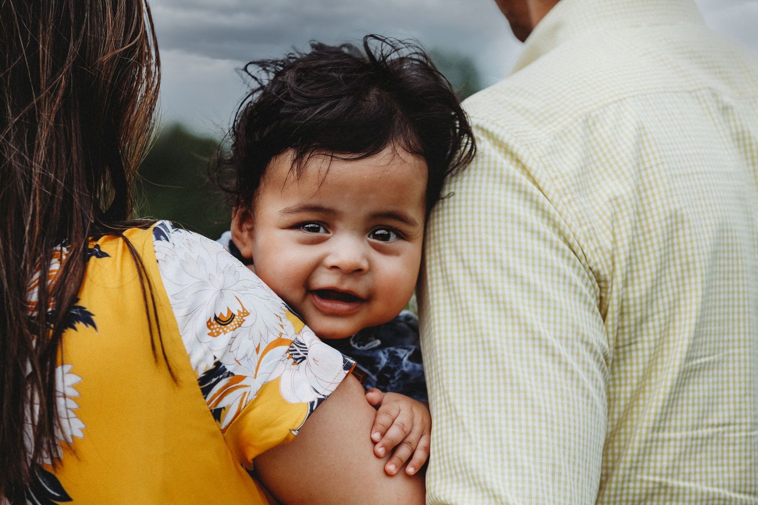 Close-up candid moment of family affection with yellow and cream clothing.