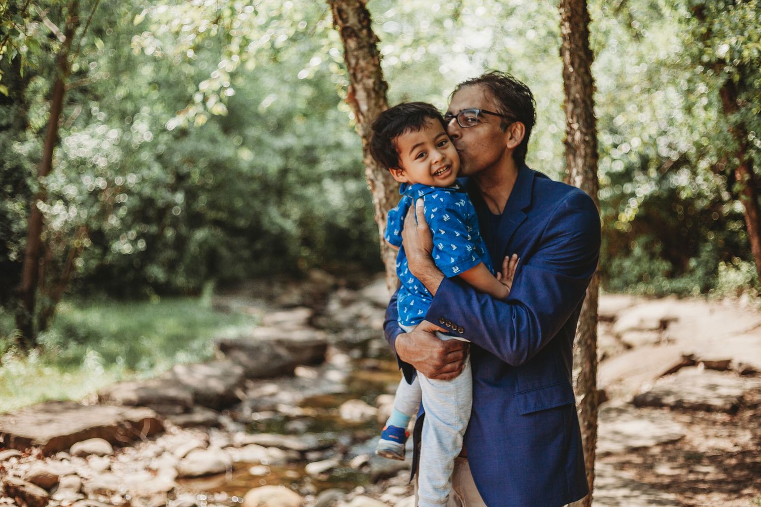 Natural outdoor family photography session among tall trees and rocks.