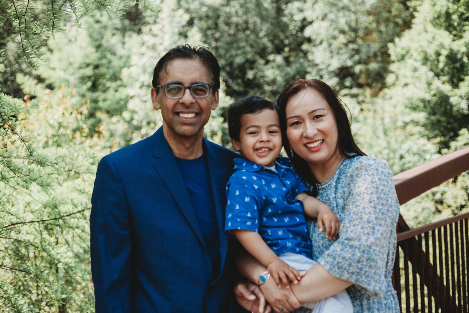 Family portrait session in a lush green outdoor setting with coordinated blue outfits.