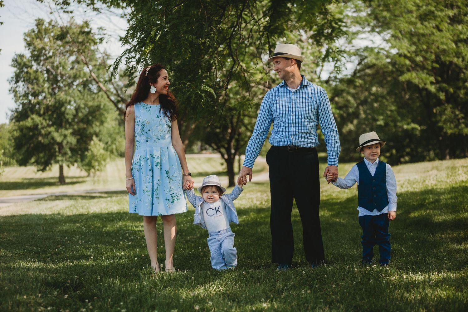 A family walks together holding hands in a park on a sunny afternoon.