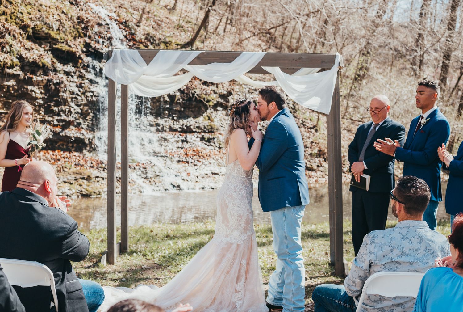 Wedding ceremony guests celebrate outdoors surrounded by decorative arches and natural scenery during a festive moment.