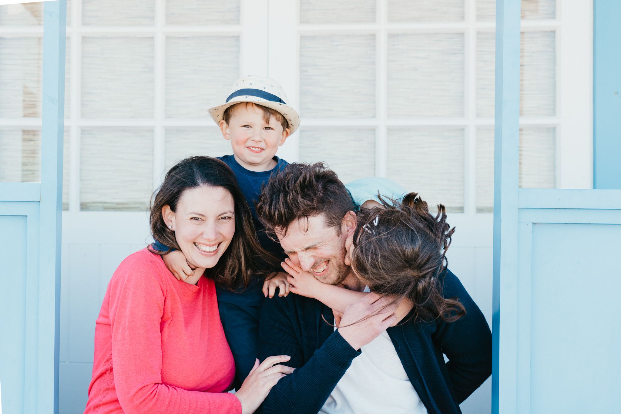 A playful family moment captured outdoors against a blue and white background.