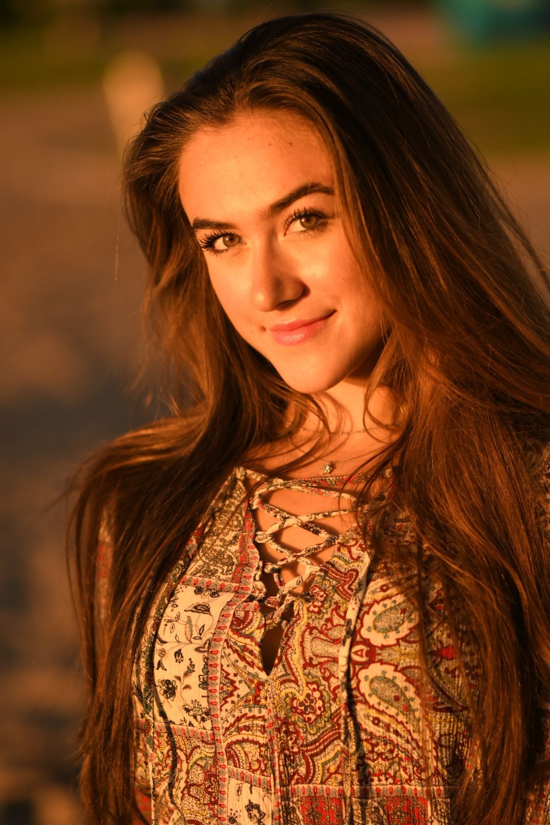 Portrait of a young woman in paisley dress during golden hour lighting.
