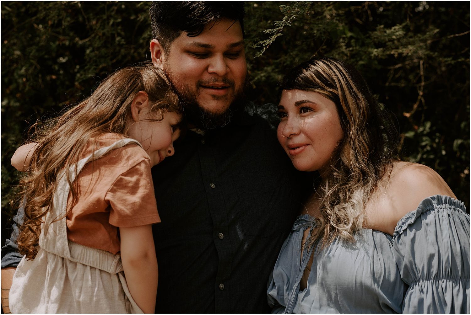 An intimate family portrait in moody lighting with warm and cool toned clothing creating contrast.