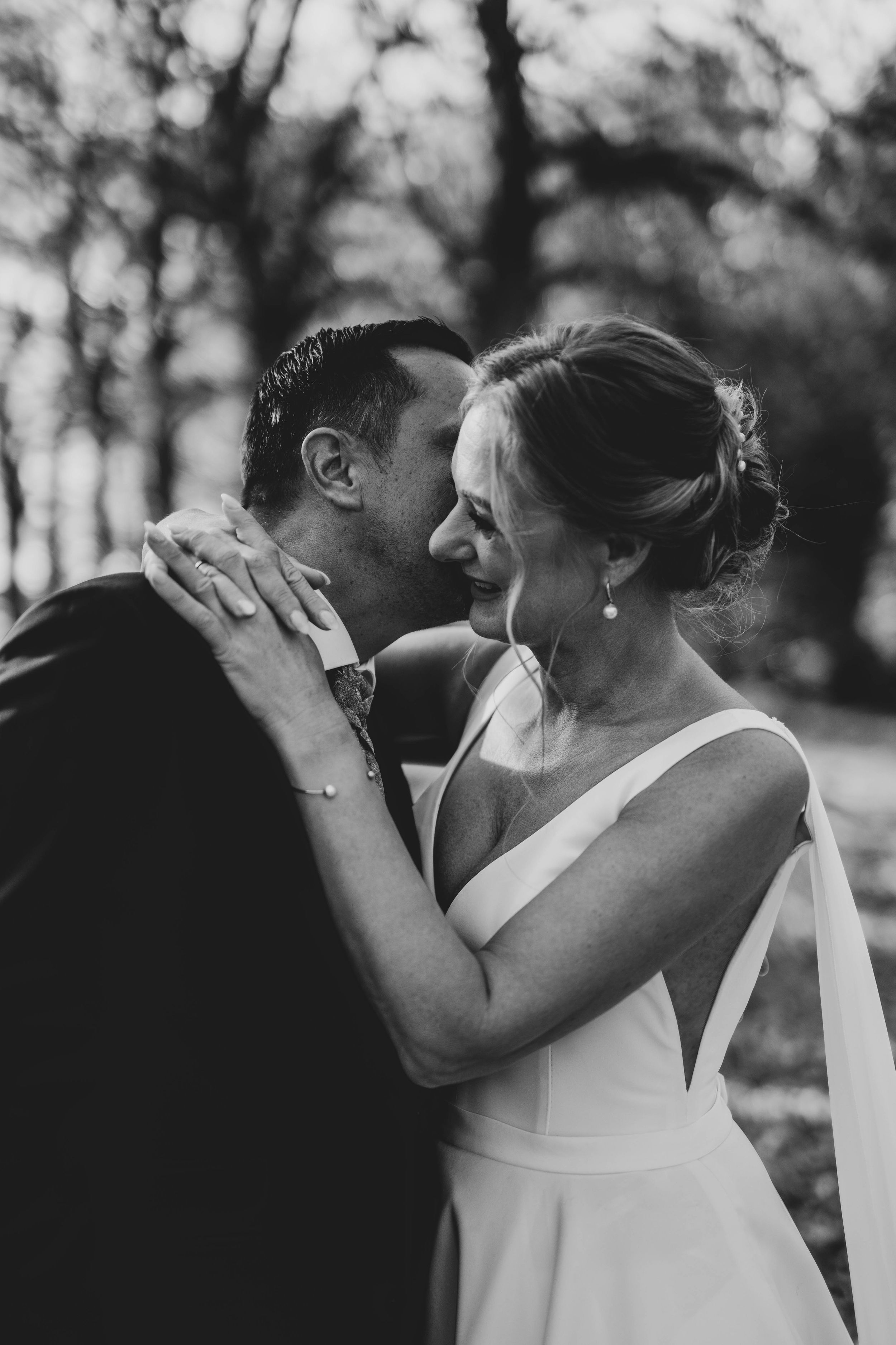 Intimate black and white portrait of newlyweds sharing tender moment outdoors.