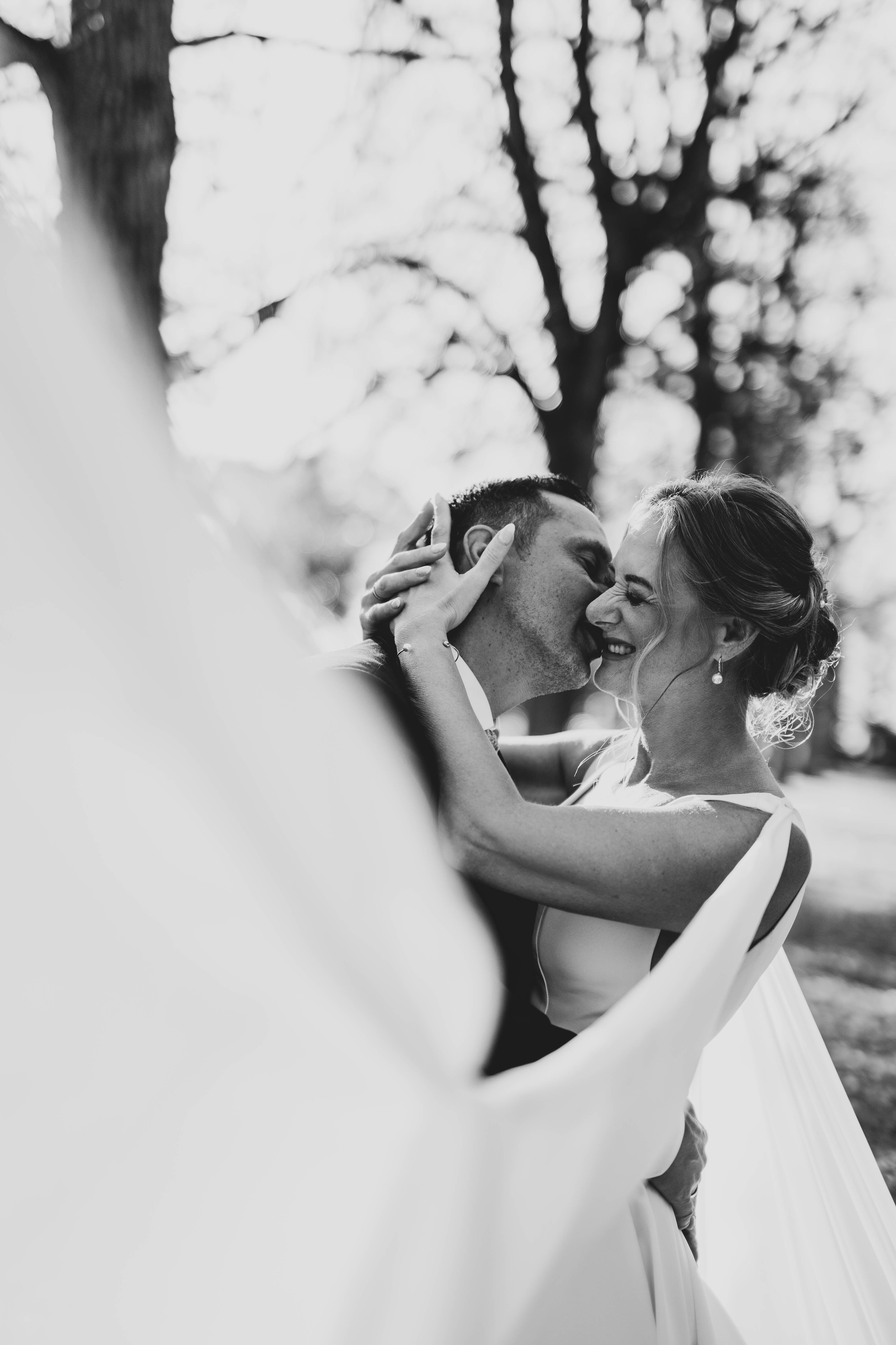 Artistic black and white close-up of a bride's veil flowing in the breeze.