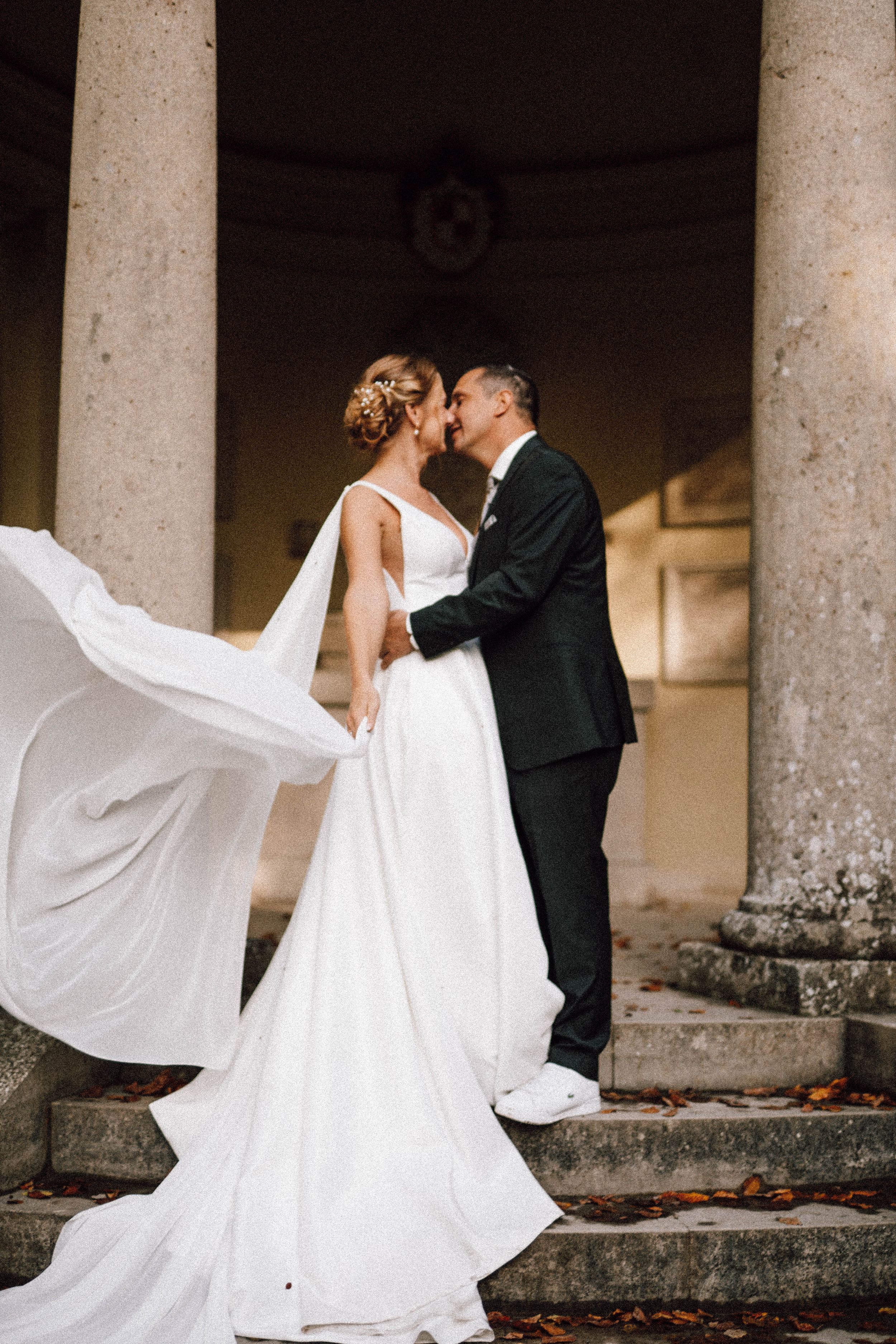 Wedding couple dancing among stone columns with bride's dress flowing dramatically.