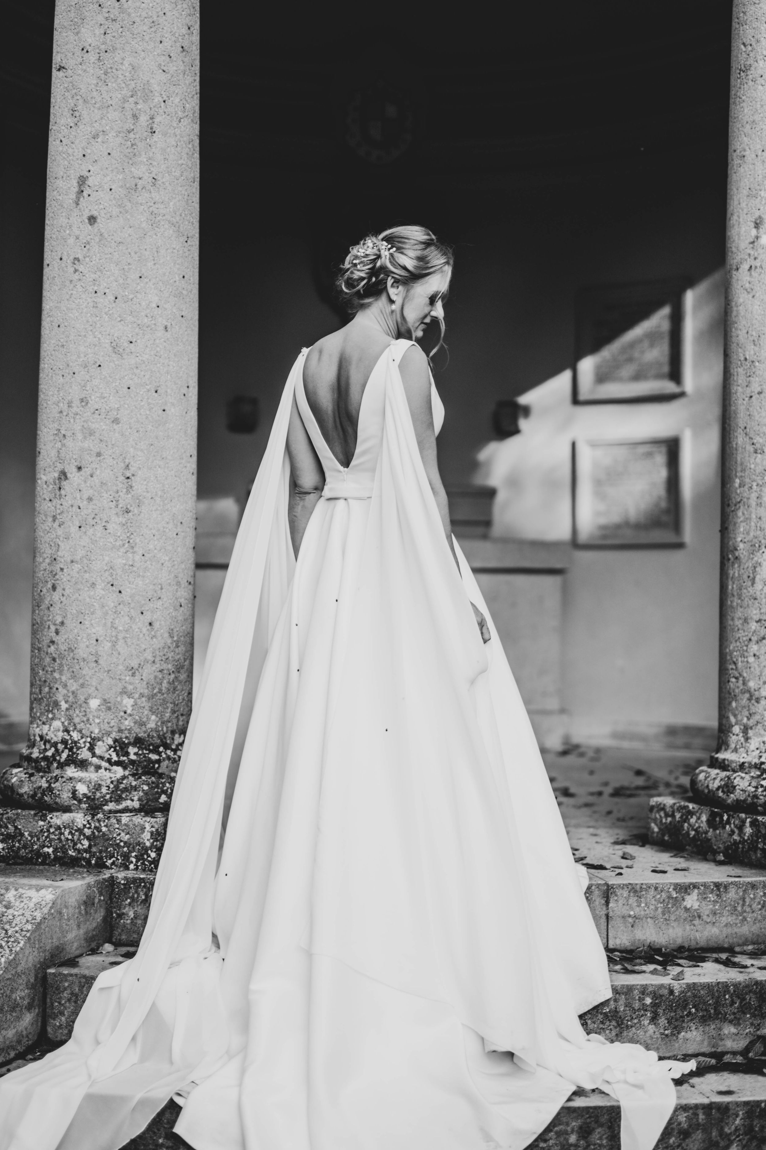 Dramatic black and white series of a flowing white wedding dress against stone pillars.
