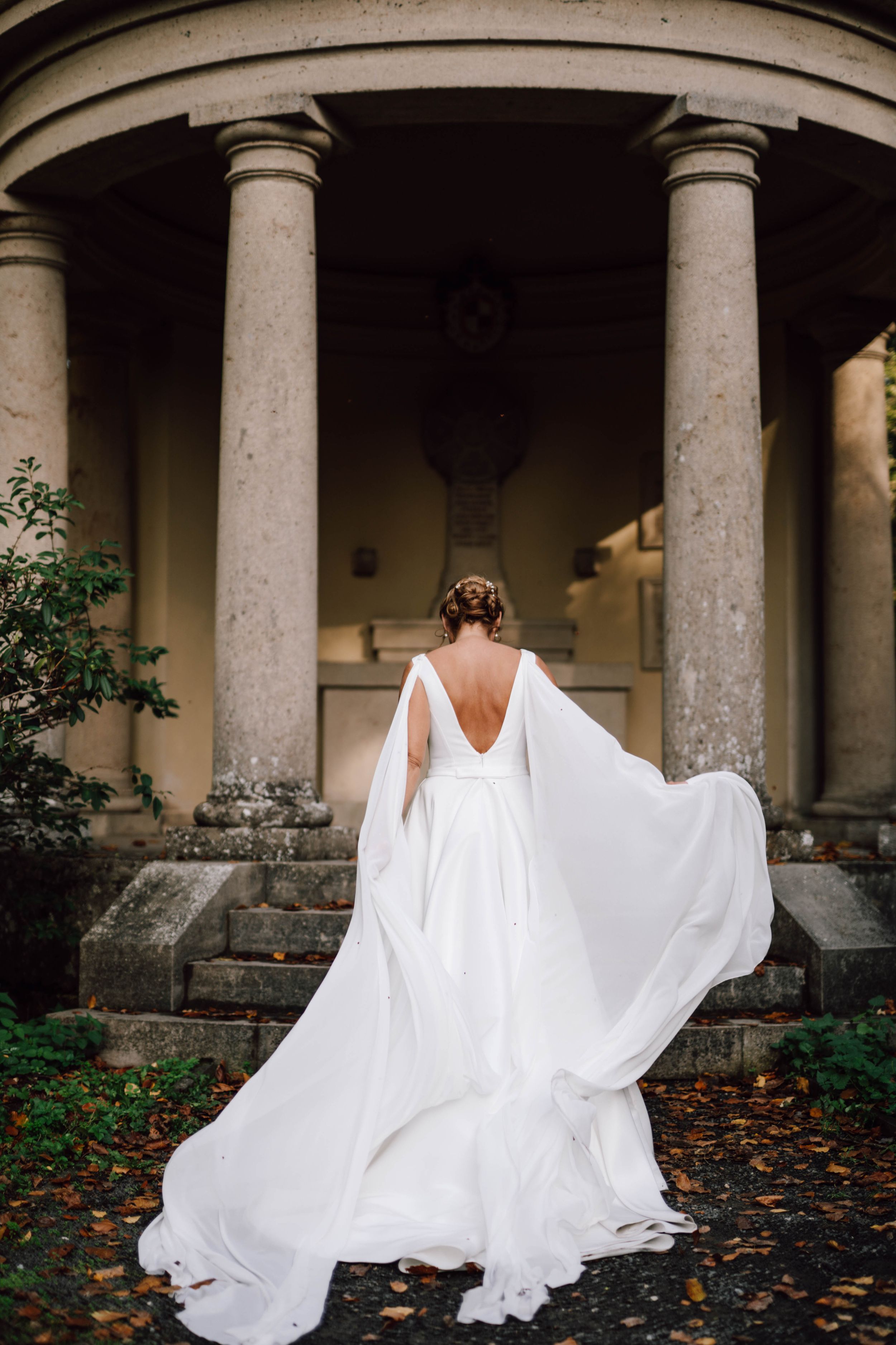 Flowing white wedding gown creates graceful movement against classical architecture.