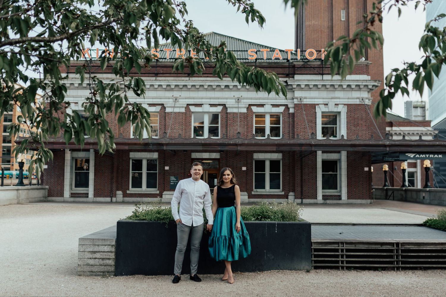 Casual couple posing in front of historic brick building in downtown area.