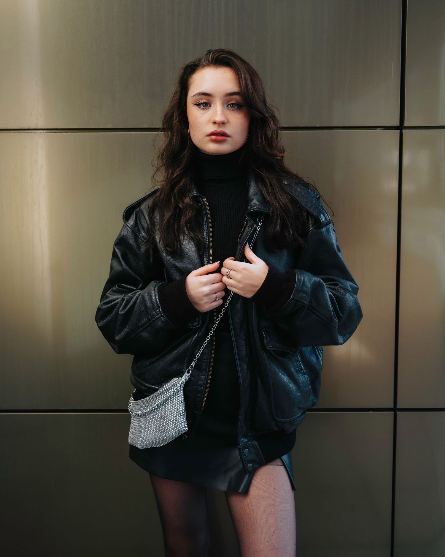 Fashion series showing black leather jacket poses against modern wall panels.