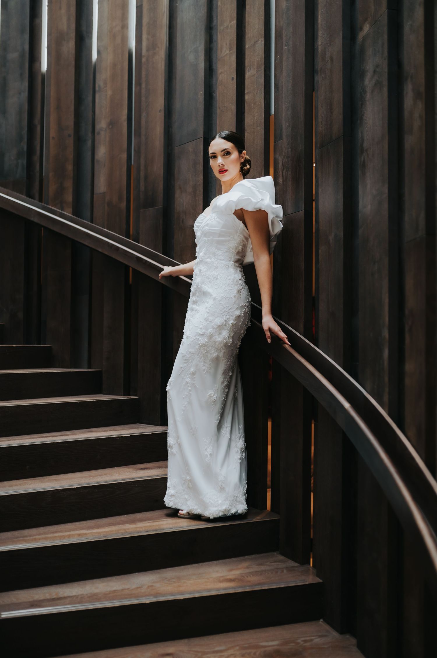 A sequence showing movement on dark wooden stairs in a white dress.