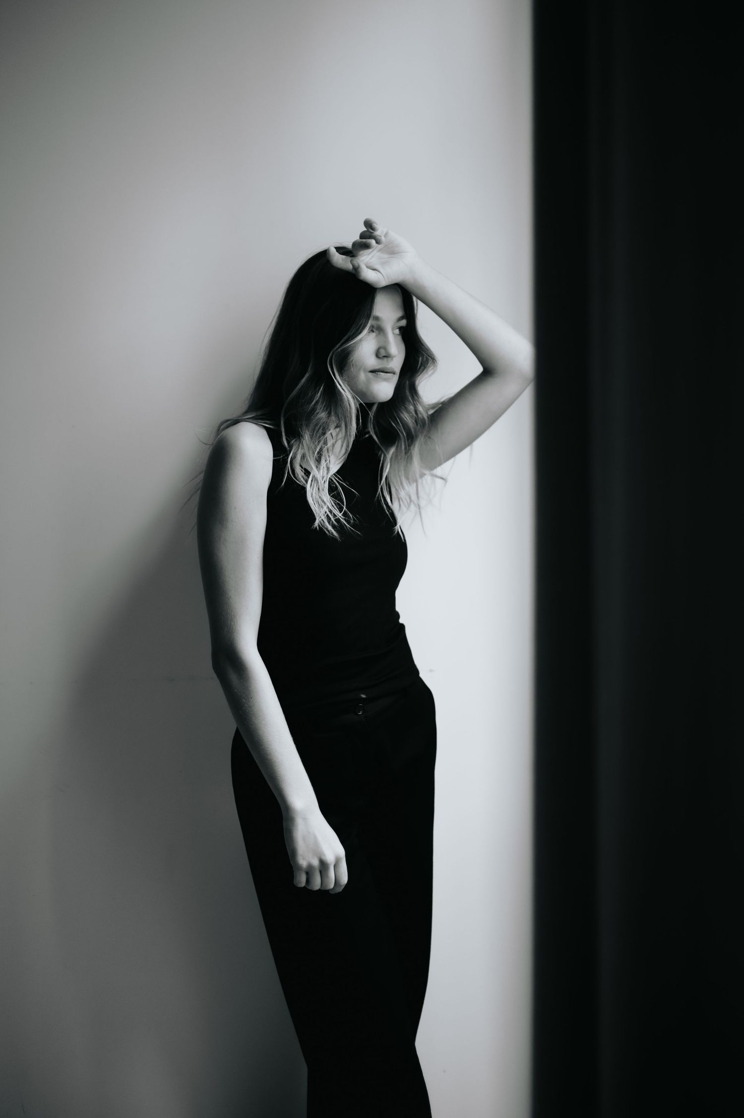 Black and white portrait series showing dramatic poses against a light wall.